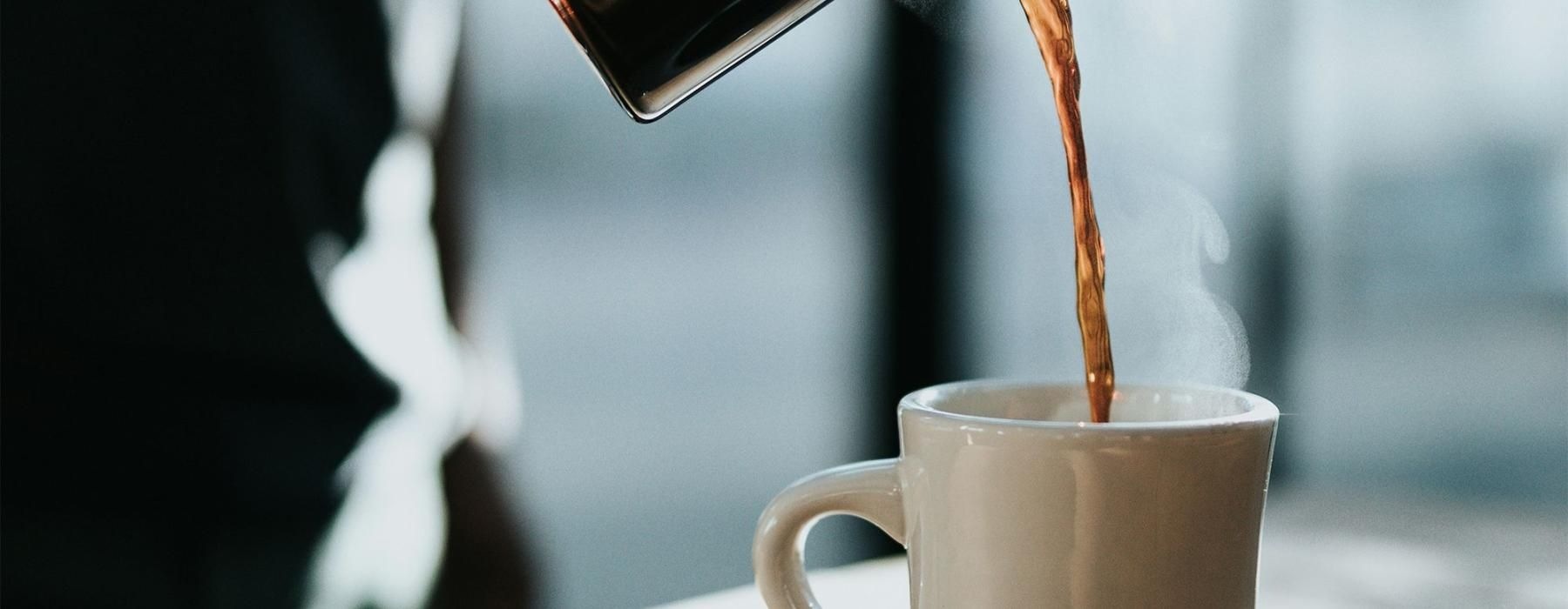 a person pouring a carafe of coffee into a cup
